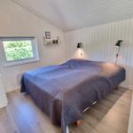 Schlafzimmer mit Bett, Fenster und Wandlampen.