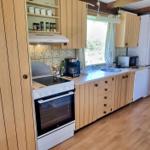 Küche mit Holzschränken, Herd, Kühlschrank und Fenster.