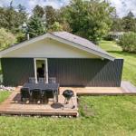 Holzhütte mit Terrasse, Grill und Garten. Tisch und Stühle für Außensitzgelegenheit.