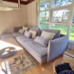 Wohnzimmer mit Sofa, Tisch und Blick auf Grünflächen.