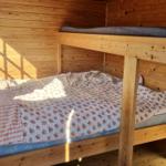 Ein Schlafzimmer mit Holzwand und Doppelbett. Oben liegt ein Matratzenkissen.