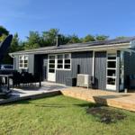 Ein Ferienhaus mit Terrasse, Garten und Außensitzgelegenheiten.