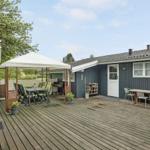 Terrasse mit Tisch, Stühlen und Sonnenschutz neben blauem Haus.