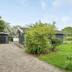 Haus mit Garten, Schuppen und Kiesweg unter blauem Himmel.