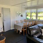 Essbereich mit Tisch, Stühlen und Sofa. Große Fenster mit Blick auf Garten.