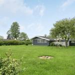 Ein graues Haus mit großem Garten und Schaukel unter Bäumen.