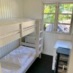 Zimmer mit Doppelstockbett, Fenster und Schreibtisch.