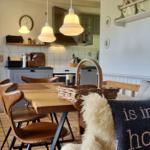 Essbereich mit Holztisch, Ledersitzen und Korb. Küche mit Arbeitsplatte und Dunstabzug.