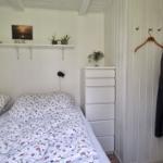 Schlafzimmer mit Doppelbett, weißen Wänden und einem Kleiderschrank.