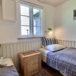 Zwei Einzelbetten mit bunten Kissen und Holzkommoden. Fenster mit Blick nach draußen.