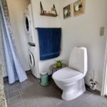 Bad mit Toilette, Waschmaschine und Duschbereich.