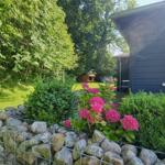 Blauer Holzhaus mit Garten, Blumen und Steinmauer.