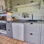 Küche mit grauen Schränken, Spüle, Kühlschrank und Kochfeld.