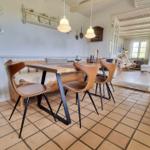 Essbereich mit Holztisch, Lederstühlen und Terrakottaboden. Blick in Wohnzimmer mit Holzfußboden.