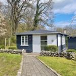 Ein kleines Haus mit blauen Wänden und weißer Tür. Vor dem Haus führt ein gepflasterter Weg.