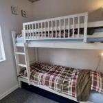 Zimmer mit Doppelstockbett, Fenster und Heizung.