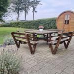 Holztisch mit Bänken auf gepflastertem Bereich neben Holzbarrique