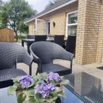 Terrasse mit Gartenmöbeln und Blumen vor einem Haus.