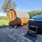 Holz-Sauna und Whirlpool auf Terrasse mit Garten und Bäumen.