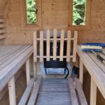 Sauna mit Holzbänken, Ofen und Fenstern zur Aussicht.