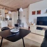 Wohn- und Küchenbereich mit Essbereich, TV und Holzdecke.