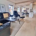 Wohnzimmer mit Sofa, Couchtisch und Essbereich. Küche und Kamin im Hintergrund.