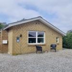 Ein kleines Haus mit Steinmauer, zwei Stühlen und einem Holzzaun.