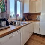 Küche mit Holzoberflächen, weißer Küchenzeile und integriertem Kühlschrank.