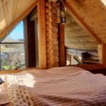 Schlafzimmer mit Holzwand, Fenster und Bett unter Dach