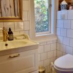 Badezimmer mit Waschbecken, Toilette und Fenster mit Blick auf Vegetation.