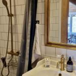 Badezimmer mit Dusche, Waschbecken und Spiegel