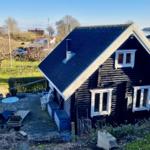 Schwarzes Holzhaus mit Terrasse und Blick auf Wasser