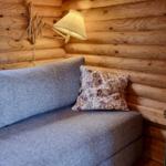 Ein Sofa mit Kissen, Wandlampe und kleiner Tisch mit Pflanze und Kerze.