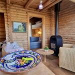 Wohnraum mit Holzwand, Sitzgelegenheiten und Kaminofen. Tisch mit dekorativem Teller.