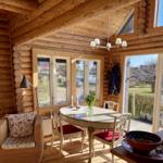 Esszimmer mit Holzdecke, Tisch und Stühlen, Fenster und Terrassentür.