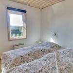 Schlafzimmer mit Doppelbett, Fenster und Holzstuhl.