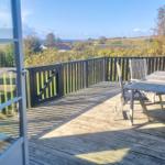 Terrasse mit Tisch und Stühlen, Blick auf Landschaft und Meer.
