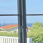 Durch das Fenster ist ein Blick auf das Meer und Häuser zu sehen.