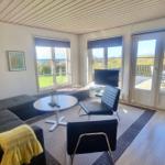 Wohnzimmer mit Sofa, Tisch, Stühlen und Blick auf Balkon und Garten.