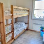 Ein Raum mit einem Holz-Etagenbett, einem Fenster und einem Spielzeugkorb.