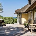 Terrasse mit Holzdielen, Stuhl, Pflanzen und Blick aufs Wasser.