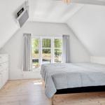 Schlafzimmer mit Dachschräge, großem Bett und Fenster mit Blick nach draußen.