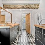 Badezimmer mit zwei Waschbecken, schwarzem Schrank und schwarz-weißem Fliesenboden.