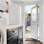 Waschmaschine neben Küchenzeile mit Holzoberfläche und weißer Tür zum Garten.