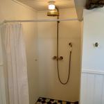 Dusche mit Duschvorhang, Duschkopf und Bodenfliesen