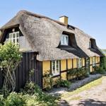 Dorfhaus mit Strohdach, gelben Wänden und Fenstern am Wasser