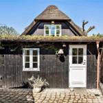 Holzhaus mit strohgedecktem Dach und weißer Tür