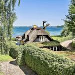 Haus mit Strohdach und Blick auf Wasser