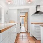 Küche mit Holzplatten, weißen Schränken und Terrakottboden