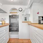 Küche mit Holzoberflächen, Edelstahlherd und Terrakottaboden.